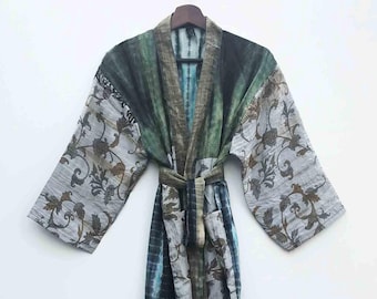 Könnte beinhalten: Langer Robe im Batik-Stil mit Gürtel. Die Robe weist eine Mischung aus Farben auf, darunter Blau-, Grün- und Grautöne. Die Ärmel und der obere Teil der Robe haben ein Blumenmuster. Die Robe hängt an einem Holzkleiderbügel.