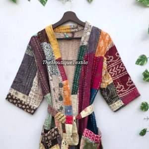 May include: A colourful patchwork quilted robe with a tie belt. The robe is made of various fabrics in shades of red, blue, green, yellow, and brown. The fabric is stitched together in a patchwork pattern. The robe has a long sleeve and a tie belt. The robe is made of cotton.