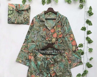 May include: A green and white floral print pajama set with a button-up top and matching pants. The set has a white trim around the edges. The text "TheBoutiqueTextile" is visible on the top.