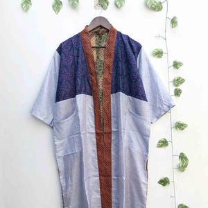 May include: A long, open-front kimono-style robe featuring a colour-blocked design. The upper section is dark blue with a purple floral pattern, while the lower body is light blue. It has a brown, polka-dot trim along the front opening and edges.
