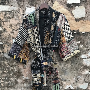 May include: Black quilted kimono robe with a patchwork design featuring various patterns and colours, including stripes, checks, and floral motifs. The robe has a sash tie and is made of cotton.