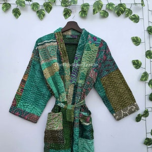 May include: A green quilted robe with a patchwork design featuring various floral and geometric patterns. The robe has a tie belt and long sleeves.