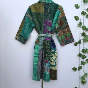 May include: A green, blue, and purple patchwork quilted robe with a tie belt. The robe has a variety of floral and geometric patterns. The text "TheBoutiqueTextile" is visible on the robe.