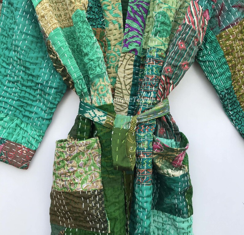 May include: A green patchwork robe with a tie belt. The robe is made of different fabrics and has a quilted design. The robe has pockets on the front.