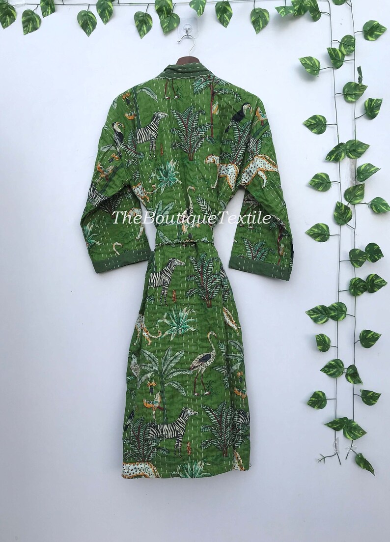 May include: A green cotton robe with a white and black animal print. The robe has a tie belt and long sleeves. The text "TheBoutiqueTextile" is printed on the robe.