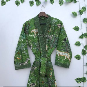 May include: Green cotton robe with a jungle print featuring animals such as zebras, leopards, and birds. The robe has a tie belt and long sleeves. The text "TheBoutiqueTextile" is printed on the robe.
