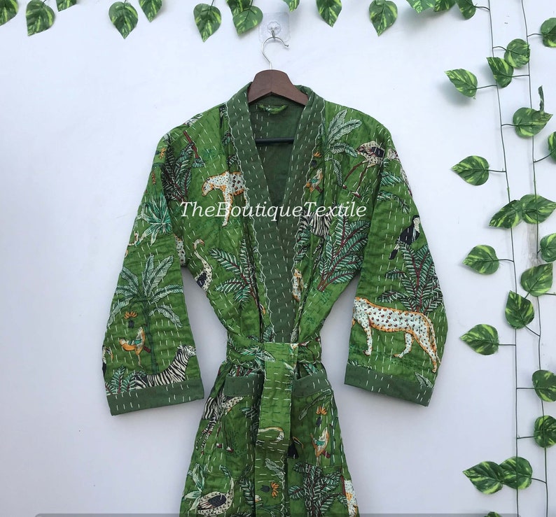 May include: Green cotton robe with a jungle print featuring animals such as zebras, leopards, and birds. The robe has a tie belt and long sleeves. The text "TheBoutiqueTextile" is printed on the robe.