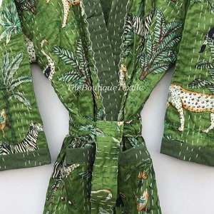 May include: Green cotton robe with a jungle print featuring zebras, leopards, and palm trees. The robe has a tie belt and pockets. The text "TheBoutiqueTextile" is printed on the robe.