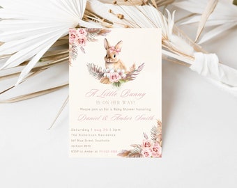 Pode incluir: Um convite para um chá de bebê com uma ilustração de um coelho rosa e detalhes florais. O texto diz "A Little Bunny Is On Her Way!" e inclui os nomes "Daniel & Amber Smith" e a data e hora do evento.