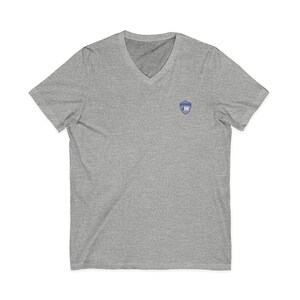 May include: A heather gray V-neck t-shirt featuring a small blue and white shield-shaped emblem on the left chest. The emblem contains the text 4DK in white lettering. The shirt has short sleeves and a standard fit, constructed from a soft fabric.