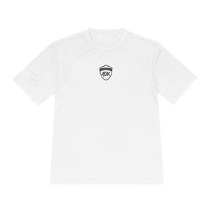Peut inclure: T-shirt blanc à manches courtes et col rond. Un logo noir en forme de bouclier avec le texte "LIFESTYLE" au-dessus et "ABK" en dessous est centré sur la poitrine. Le t-shirt est en tissu léger et respirant.