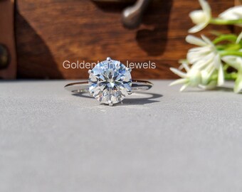 May include: A silver ring with a large, clear, round diamond solitaire.