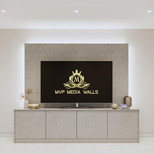May include: A modern living room with a flat screen TV mounted on a wall with a light grey stone finish. The TV is displaying a logo with the text "MVP MEDIA WALLS". The TV is mounted above a light grey cabinet with three doors.