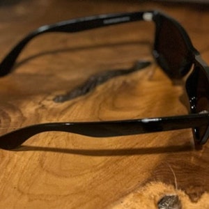 May include: Black sunglasses with dark lenses. The sunglasses are made of plastic and have a simple design.