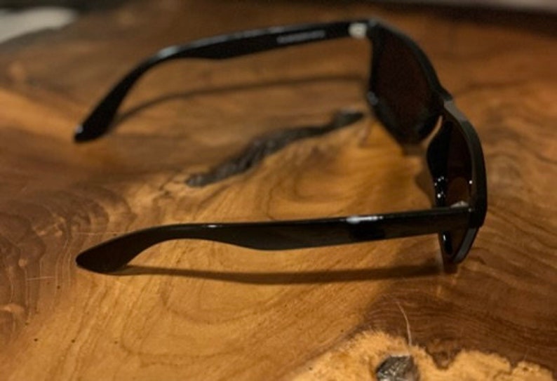 May include: Black sunglasses with dark lenses. The sunglasses are made of plastic and have a simple design.