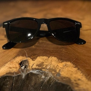 May include: Black sunglasses with a classic aviator style frame.