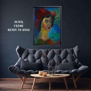 May include: A framed portrait of a woman wearing a red hat with a flower, set against a colorful background. The artwork is displayed above a gray sofa with black pillows. The text "BLACK FRAME READY TO HANG" is visible.
