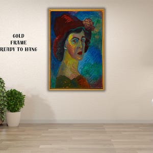 May include: A framed portrait of a person wearing a red hat with a floral accent. The artwork features a colorful palette with blue, green, and yellow hues. The gold frame is ready to hang.