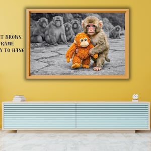 Peut inclure: Impression encadrée avec une photo en noir et blanc de singes, l'un d'eux tenant un jouet orange. Le cadre est marron clair. Le texte "LIGHT BROWN FRAME READY TO HANG" est visible. Prêt à être accroché.