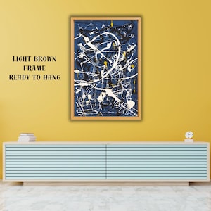 May include: Abstract art print in a light brown frame, ready to hang. The artwork features a dark blue background with white and yellow paint splatters. The text "LIGHT BROWN FRAME READY TO HANG" is visible.