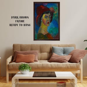 May include: A framed portrait of a woman wearing a red hat, with a dark brown frame. The painting features vibrant colors and brushstrokes. Text on the wall reads "DARK BROWN FRAME READY TO HANG". The artwork is displayed above a sofa with pillows.