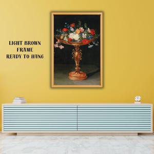 May include: A framed painting featuring a still life of flowers in a decorative bronze-colored bowl. The painting is in a light brown frame and is ready to hang. The text on the wall says "LIGHT BROWN FRAME READY TO HANG".