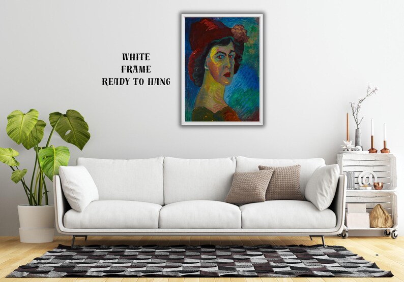 May include: A framed portrait of a woman wearing a red hat with a flower, painted in vibrant colors. The artwork is displayed above a white sofa, with the text "WHITE FRAME READY TO HANG" visible.