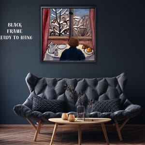 May include: A framed painting depicts a person gazing out a window at a snowy landscape. The artwork features a table set with a teapot, plate, and food. The text "BLACK FRAME READY TO HANG" is visible.