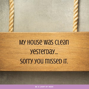 Könnte beinhalten: Ein Holzschild mit dem Text "My House was CLEAN yesterday... sorry you MISSED IT." hängt an einem Seil. Das Schild befindet sich auf einem grauen Hintergrund. Der Text "BE A LIGHT BY HEIDI" befindet sich am unteren Rand des Bildes.