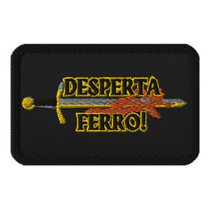 May include: A black embroidered patch with a gold sword and the text "DESPIERTA FERRO!" in gold.