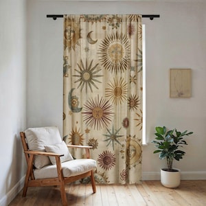 May include: Beige curtain with a celestial design featuring suns, moons, and stars in shades of brown, red, and blue. The curtain hangs in front of a window, with a wooden chair and a potted plant in the room.