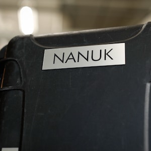 May include: A black hard-shell case with a silver label that reads "NANUK".
