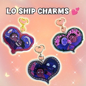 Può includere: Tre ciondoli a forma di cuore con illustrazioni di cartoni animati e portachiavi color oro. I ciondoli presentano coppie in varie scene, con la scritta "LO SHIP CHARMS" in alto. Lo sfondo è un gradiente di rosa e arancione.