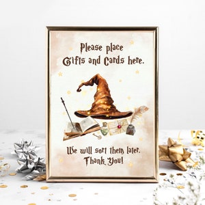 May include: A sign with a brown witch hat and stars on a beige background. The sign says "Please place Gifts and Cards here. We will sort them later. Thank You!"
