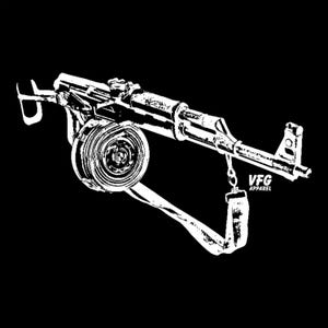 Peut inclure: Une illustration graphique blanche à haut contraste sur fond noir représentant un fusil avec un chargeur tambour circulaire et une sangle de transport. Le texte VFG APPAREL est imprimé en blanc près du canon de l'arme dans ce design détaillé.