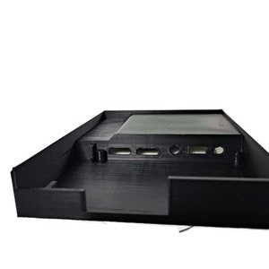 May include: Black plastic case with a rectangular opening and several small holes. The case has a textured surface.