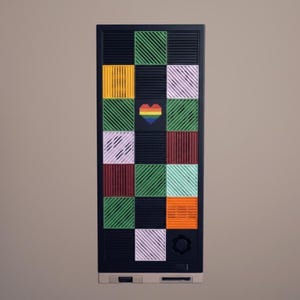 Pode incluir: Um objeto retangular preto com um padrão de grade de quadrados coloridos. Os quadrados são em tons de verde, amarelo, laranja, vermelho e branco, com um coração arco-íris no centro. O objeto tem um botão e uma ranhura na parte inferior.