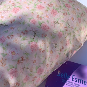 May include: A pink silk pillowcase with a floral pattern of pink roses and green leaves. The pillowcase is made of 100% mulberry silk and is certified OEKO-TEX Standard 100. The pillowcase is packaged in a purple box with the text "Belle Esmee 100% Mulberry Silk Pillowcase OEKO-TEX Certified Top Grade 6A - 22 Momme www.belleesmee.com"