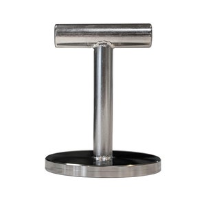 Op de afbeelding: Een roestvrijstalen T-vormig object met een cirkelvormige basis. De verticale paal verbindt met een horizontale balk. De basis is een platte, zwarte schijf met een zilveren rand. Het object is waarschijnlijk een displaystandaard of een vergelijkbaar product.