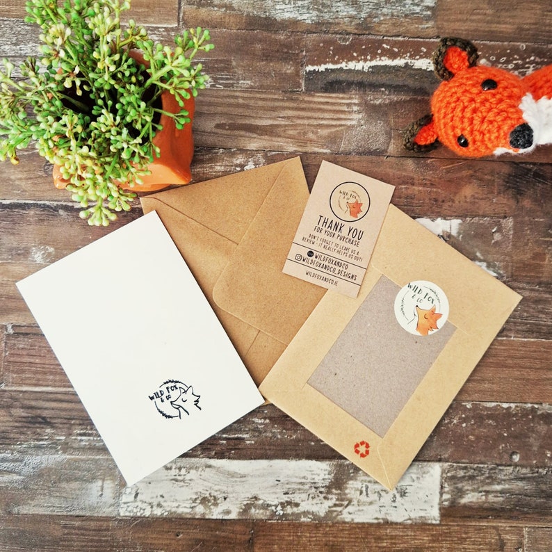 Puede incluir: Una tarjeta de agradecimiento con una ilustraci&oacute;n de zorro y el texto "Gracias por su compra. &iexcl;No olvide dejarnos una rese&ntilde;a! &iexcl;Realmente nos ayuda!"  #wildfoxknits #wildfoxknitsdesigns wildfoxknits.co.uk", un sobre marr&oacute;n con una pegatina de zorro y un zorro naranja de crochet.