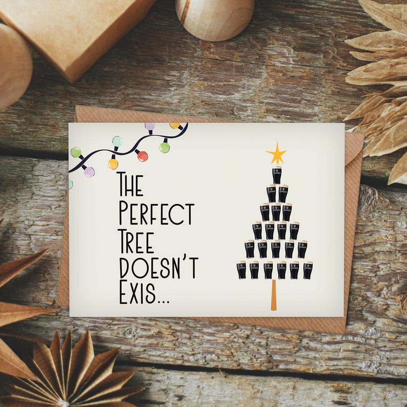 Puede incluir: Una tarjeta de Navidad con fondo blanco y una ilustraci&oacute;n en blanco y negro de un &aacute;rbol de Navidad hecho de vasos de cerveza. El texto de la tarjeta dice "The perfect tree doesn't exis..." con una cadena de luces de colores sobre el &aacute;rbol.