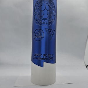 May include: A blue trophy with a white base. The trophy has a logo for the Microsoft UK Football Club and the text "MSFC UK FIFA Champion 2024".