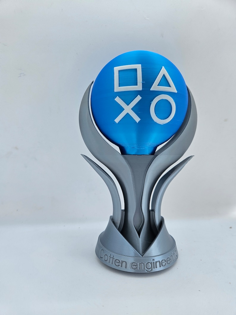 May include: A 3D printed trophy with a blue sphere on top. The sphere has the PlayStation button symbols on it. The base of the trophy is silver and has the words "Cotton Engineering" inscribed on it.