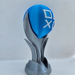 May include: A 3D printed trophy with a blue sphere on top. The sphere has a white PlayStation logo on it. The base of the trophy is silver and has the words "Cotten eng" inscribed on it.