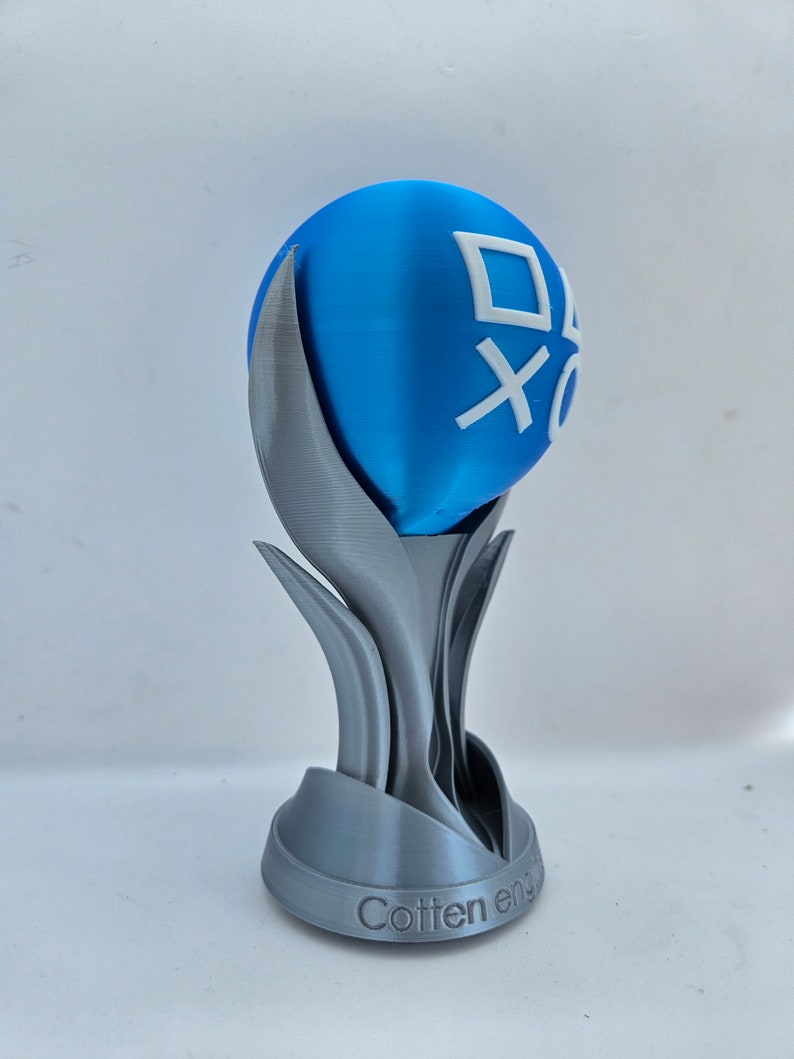 May include: A 3D printed trophy with a blue sphere on top. The sphere has a white PlayStation logo on it. The base of the trophy is silver and has the words "Cotten eng" inscribed on it.