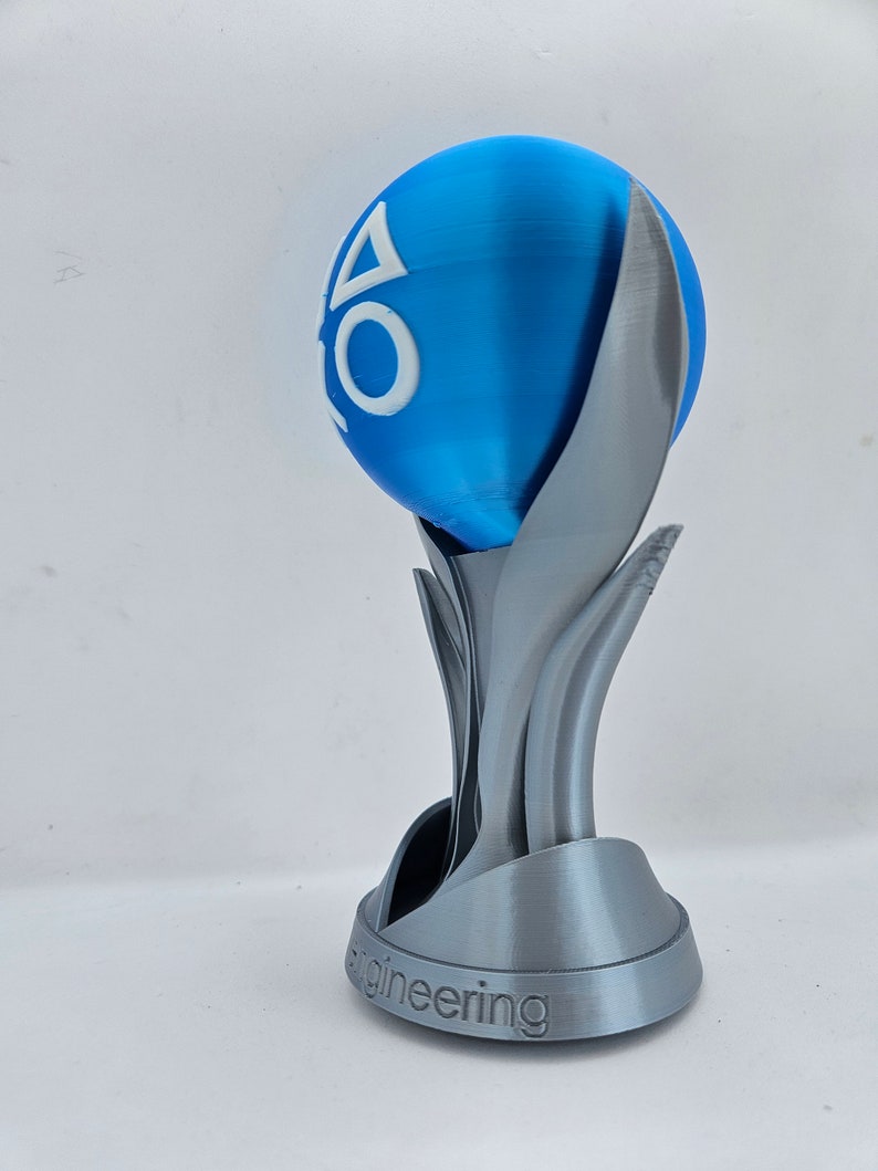 May include: A silver 3D printed trophy with a blue sphere on top. The sphere has the PlayStation logo on it. The base of the trophy says "Engineering".