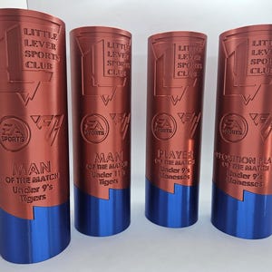 May include: Four red and blue trophy cups with the text "Little Lever Sports Club" and "EA Sports" on them. The trophies are for "Man of the Match" for different age groups.