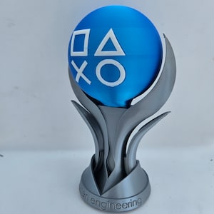 May include: A silver trophy with a blue sphere on top. The sphere has the PlayStation button symbols in white. The base of the trophy says "open engineering".