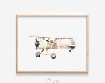 Op de afbeelding: Een aquarel schilderij van een vintage vliegtuig in beige en blauwe kleuren. Het vliegtuig vliegt met zijn vleugels uitgespreid. Het schilderij is ingelijst in een licht houten lijst.