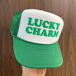 a hand holding a green and white lucky charm hat
